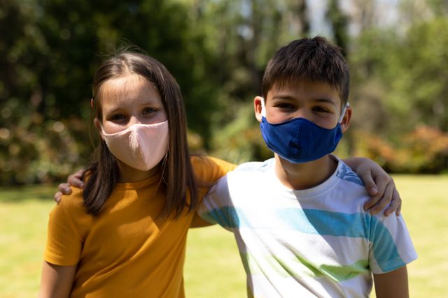 A caucasian boy and a girl wearing facemasks outside on a bright and sunny day - Download Free Stock Photos Pikwizard.com