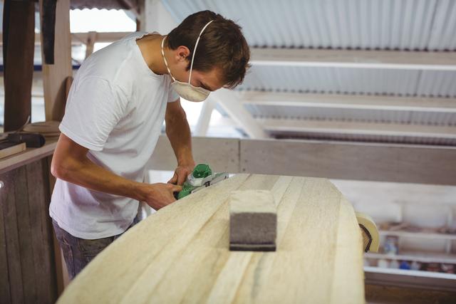 Man making surfboard in workshop