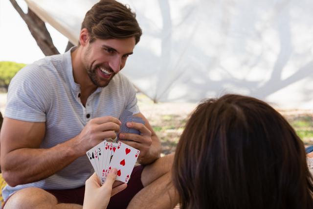 Smiling man playing cards with woman in tent - Download Free Stock Photos Pikwizard.com