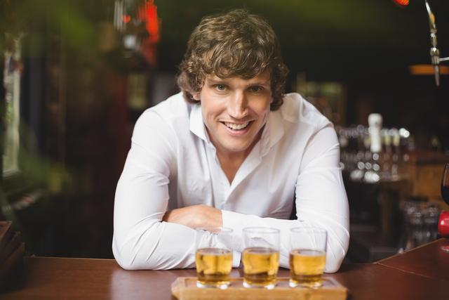Portrait of bartender with tray of whisky shot glasses at bar counter - Download Free Stock Photos Pikwizard.com