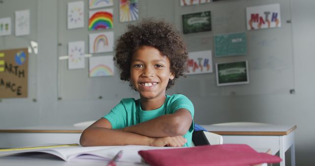 Image of happy biracial boy sitting at desk in classsroom - Download Free Stock Photos Pikwizard.com