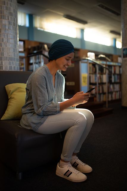 Side view of mixed race woman using smartphone in library - Download Free Stock Photos Pikwizard.com