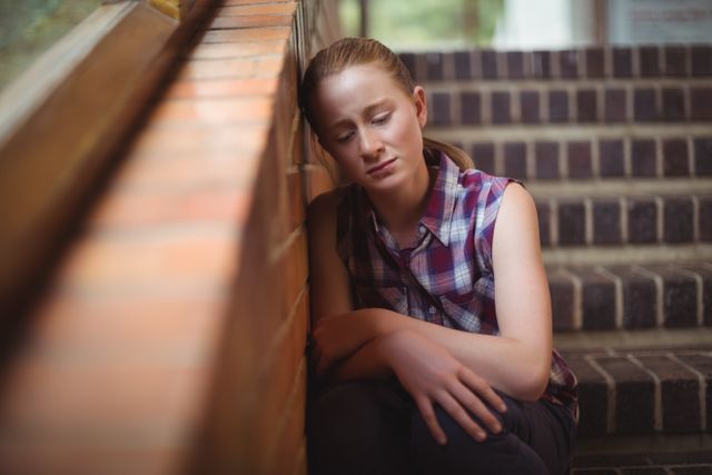 Sad schoolgirl sitting alone on staircase - Download Free Stock Photos Pikwizard.com