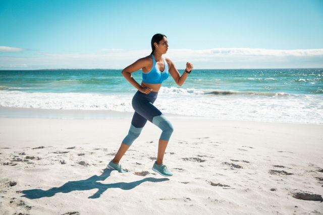 Mixed race woman exercising outdoors wearing wireless earphones running at the beach - Download Free Stock Photos Pikwizard.com