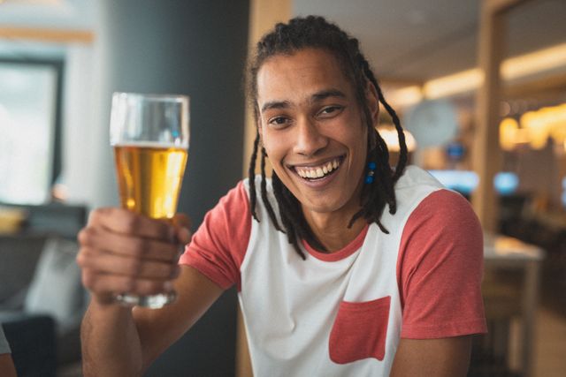 Mixed race man smiling and drinking beer with friend - Download Free Stock Photos Pikwizard.com