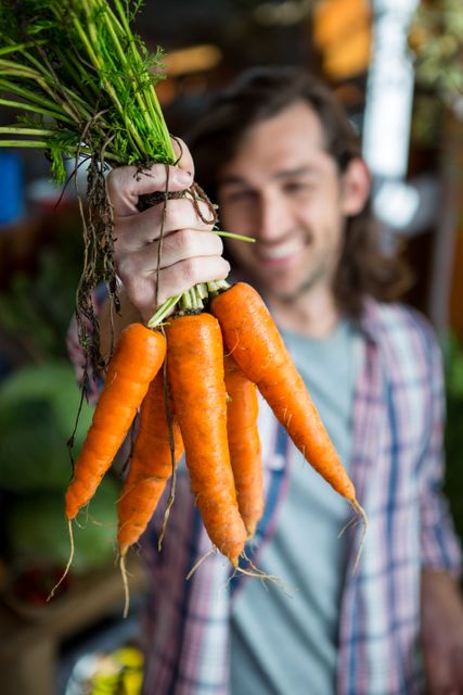 Man holding carrots in organic shop - Download Free Stock Photos Pikwizard.com