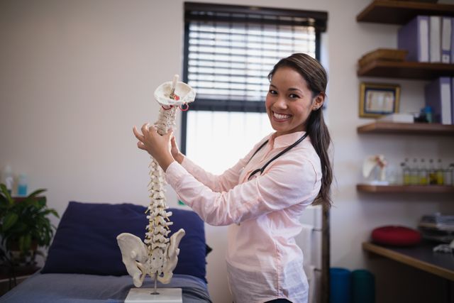 Portrait of smiling female therapist examining artificial spine on bed - Download Free Stock Photos Pikwizard.com
