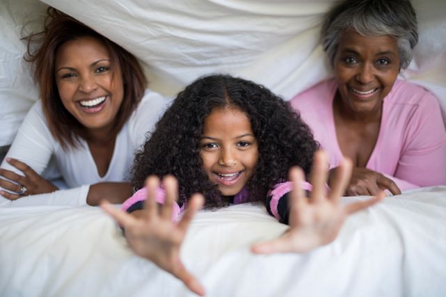 Portrait of happy family lying under blanket on bed in bedroom - Download Free Stock Photos Pikwizard.com