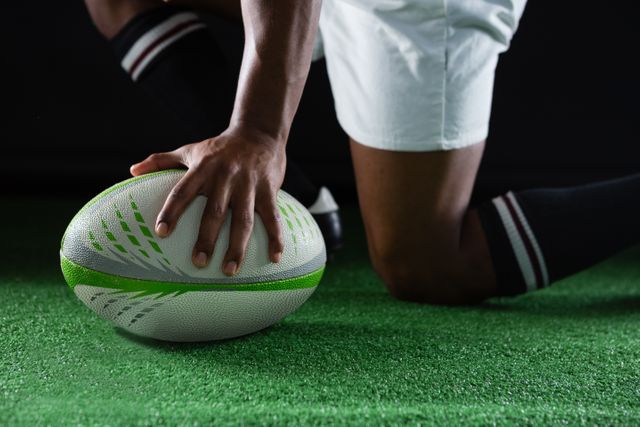 Side view of sportsman kneeling while holding rugby ball - Download Free Stock Photos Pikwizard.com