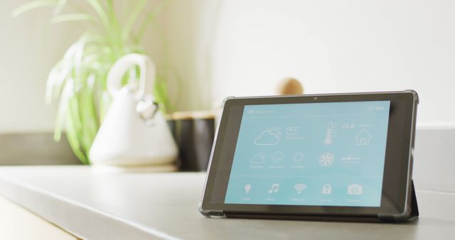 Image of tablet with smart home interface screen on worktop in sunny, modern kitchen. Technology, control, ecology and domestic life.