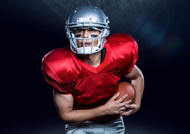 American football player holding ball against black background - Download Free Stock Photos Pikwizard.com