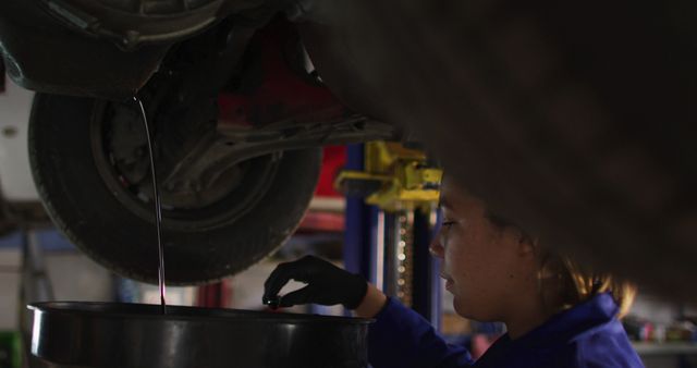 Female mechanic changing oil of the car at a car service station. automobile repair service