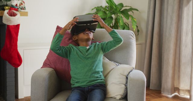 Happy african american boy wearing vr headset and having fun at christmas time. christmas, festivity and communication technology.