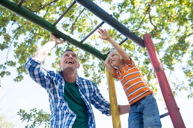 Low angle view of father and son playing on jungle gym - Download Free Stock Photos Pikwizard.com