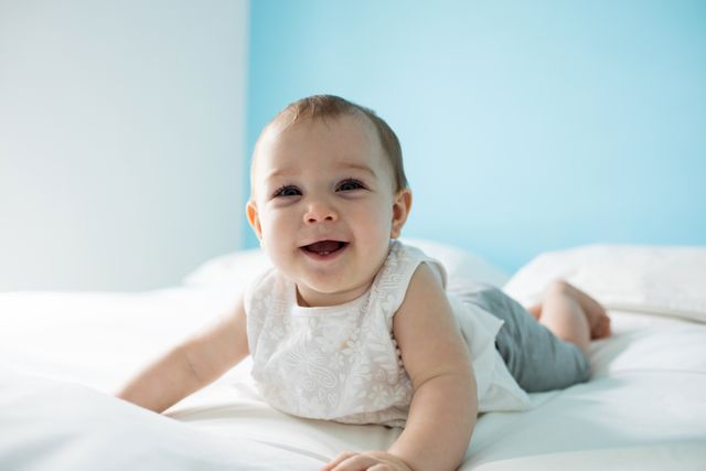 Cute smiling baby girl on bed in bedroom