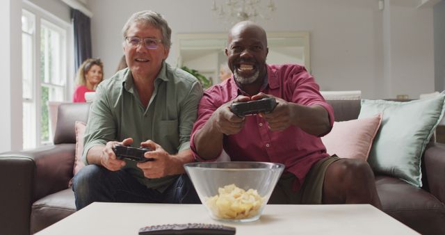 Image of happy diverse male senior friends playing image games. retirement lifestyle, spending quality time with friends and technology.