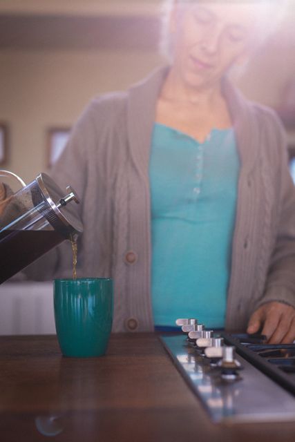 Caucasian senior woman pouring cup of coffee in sunny kitchen - Download Free Stock Photos Pikwizard.com