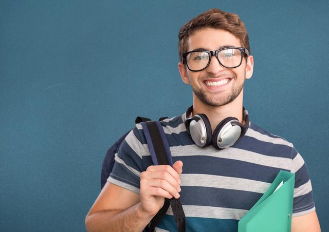 Portrait of a happy college boy with headphones carrying bag and file - Download Free Stock Photos Pikwizard.com