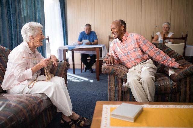Cheerful senior man talking with woman at retirement home