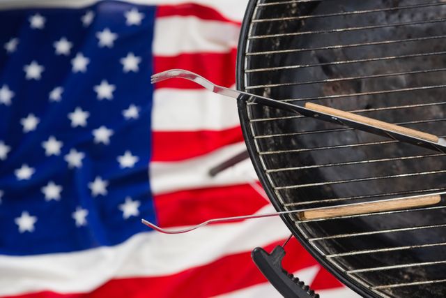 Close-up of tong arranged on barbeque against American flag