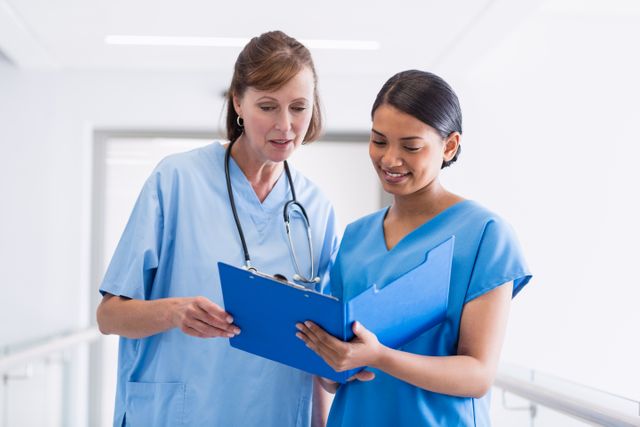 Nurse and doctor discussing over clipboard - Download Free Stock Photos Pikwizard.com