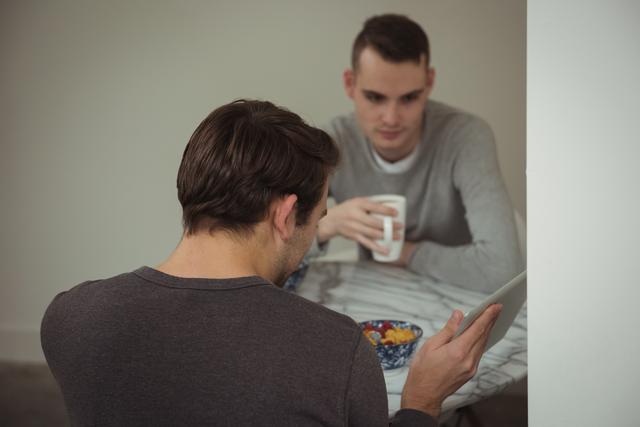 Gay couple looking at digital tablet while having breakfast - Download Free Stock Photos Pikwizard.com