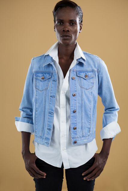 Androgynous man in denim jacket posing against beige background - Download Free Stock Photos Pikwizard.com