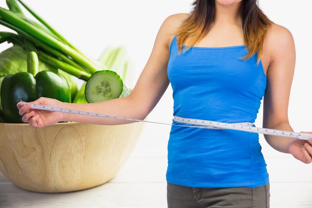 Midsection of woman measuring waist against vegetables in background - Download Free Stock Photos Pikwizard.com