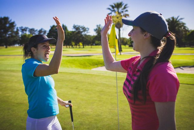 Two caucasian woman high fiving each other at golf course - Download Free Stock Photos Pikwizard.com