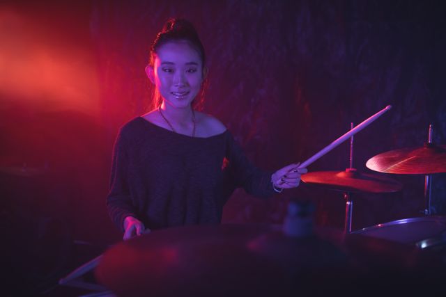 Portrait of smiling female drummer playing drum kit in nightclub - Download Free Stock Photos Pikwizard.com