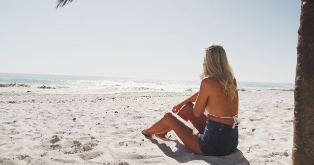 Happy caucasian woman sitting on beach and looking at sea. Lifestyle, realxation, nature, free time and vacation.