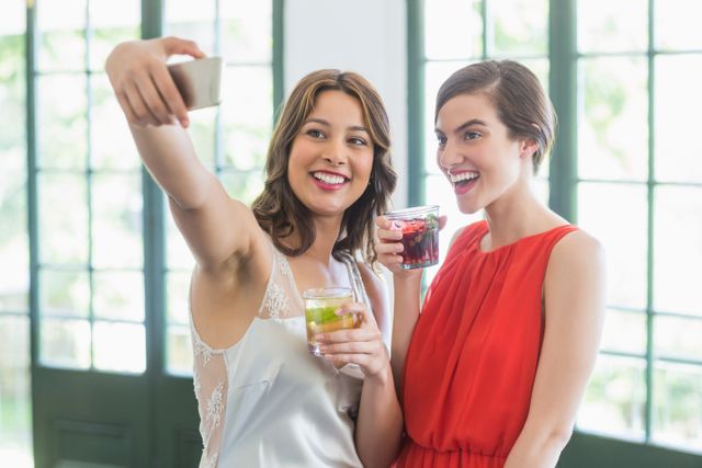 Friends taking a selfie while holding cocktail glasses - Download Free Stock Photos Pikwizard.com