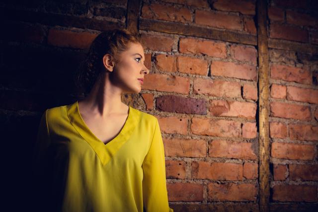 Woman standing against brick wall - Download Free Stock Photos Pikwizard.com