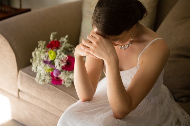 High angle view of upset bride sitting by bouquet on sofa - Download Free Stock Photos Pikwizard.com