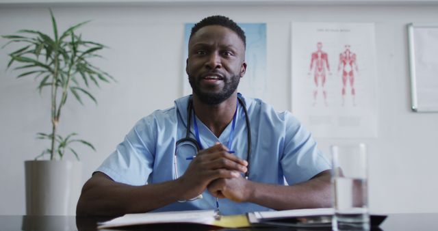 African american male doctor at desk talking and gesturing during image call consultation. telemedicine, online healthcare services during quarantine lockdown.