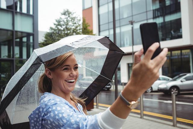 Beautiful woman holding umbrella while taking selfie - Download Free Stock Photos Pikwizard.com