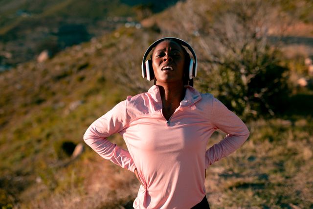 Fit african american woman exercising in countryside, wearing headphones - Download Free Stock Photos Pikwizard.com