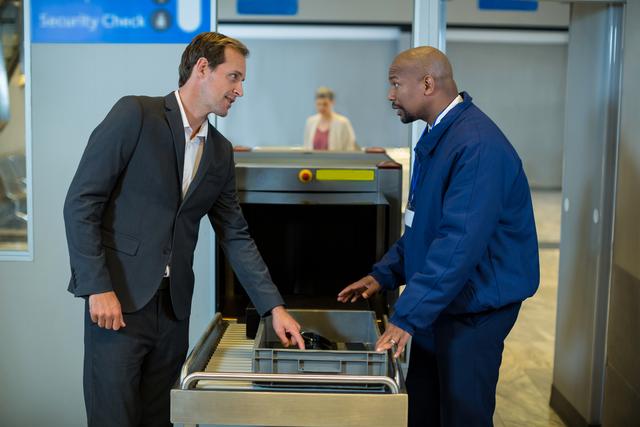 Airport security officer interacting with commuter while checking a package - Download Free Stock Photos Pikwizard.com