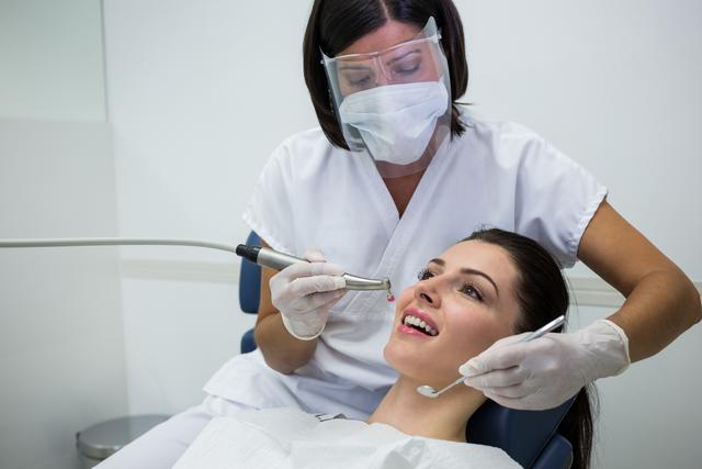 Dentist examining a female patient with tools at dental clinic 