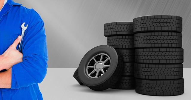 Mechanic with arms crossed and tyres against grey background - Download Free Stock Photos Pikwizard.com