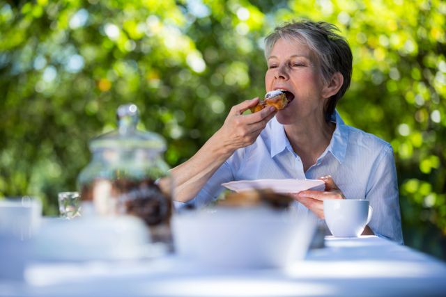 Senior woman eating sweet food in garden - Download Free Stock Photos Pikwizard.com