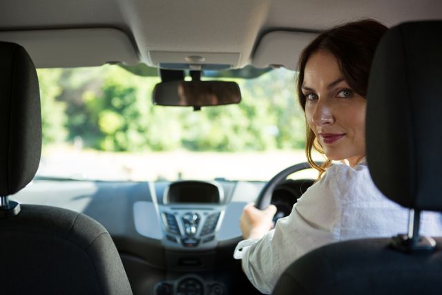 Woman smiling while driving a car - Download Free Stock Photos Pikwizard.com