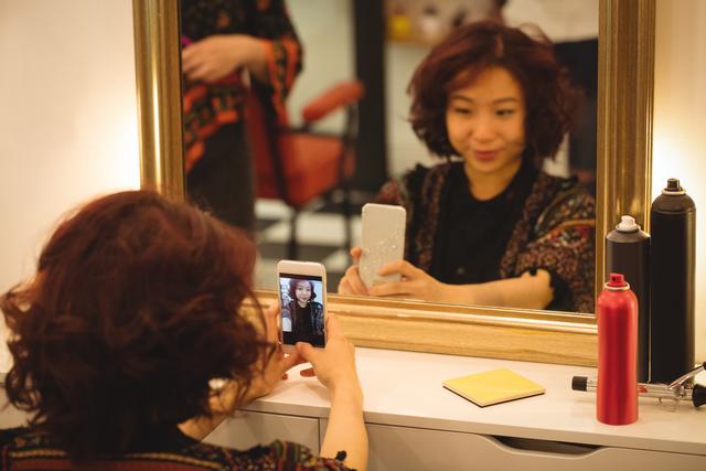 Woman taking mirror selfie at hair salon - Download Free Stock Photos Pikwizard.com