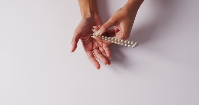 Image of hands of caucasian woman holding plaster with pills on white background. medicine, health, cancer awareness concept digitally generated image.
