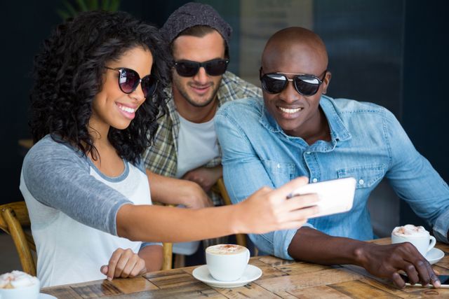 Friends wearing sunglasses while taking selfie in coffee shop - Download Free Stock Photos Pikwizard.com