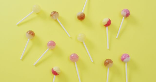 Image of multicoloured lollipops on yellow background. colourful fun food, candy, snacks and sweets concept.