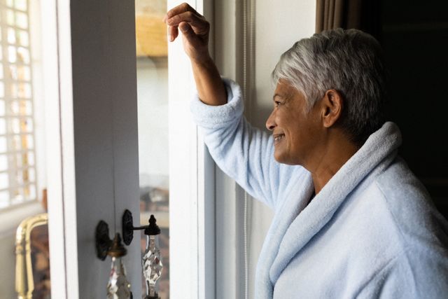 Senior african american woman standing by a window in a bedroom - Download Free Stock Photos Pikwizard.com