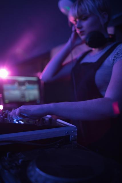 Female dj listening to headphones while playing music - Download Free Stock Photos Pikwizard.com