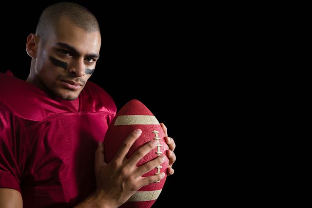Determined American football player holding a football with both his hands - Download Free Stock Photos Pikwizard.com