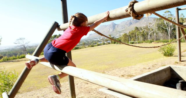 A child engages in outdoor play on a rope climbing structure, with copy space. Capturing the essence of childhood adventure, the image reflects the joy and energy of youthful playtime in a natural setting.